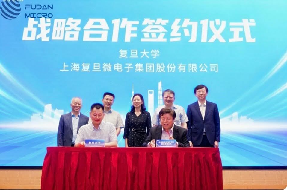 Officials from Fudan University and Shanghai Fudan Microelectronics Group stand and sit behind a red table for a strategic-cooperation signing ceremony in July 2025.